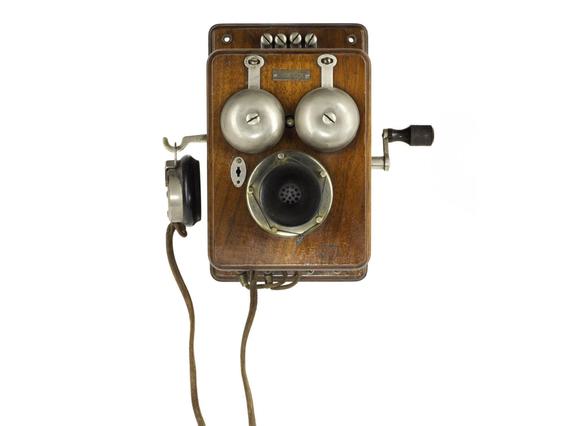 Wooden wall-mounted telephone with two bells, a crank, and an earpiece hanging from the side.
